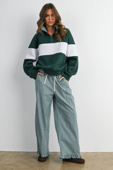 woman wearing a green and gray zip-up pullover and gingham wide-leg pants with ruffled hems