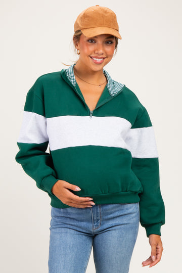woman wearing a green and gray striped maternity sweatshirt with a checkered collar and holding her baby bump