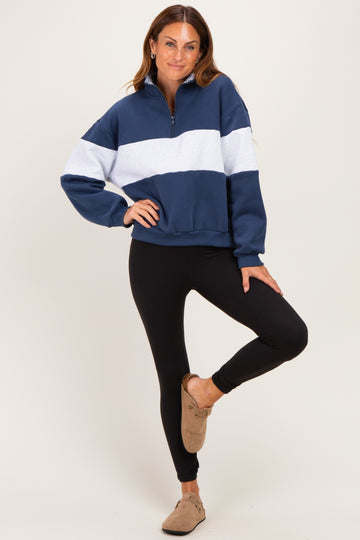 woman wearing a navy blue and white color block half-zip pullover sweatshirt with black leggings and slip-on shoes