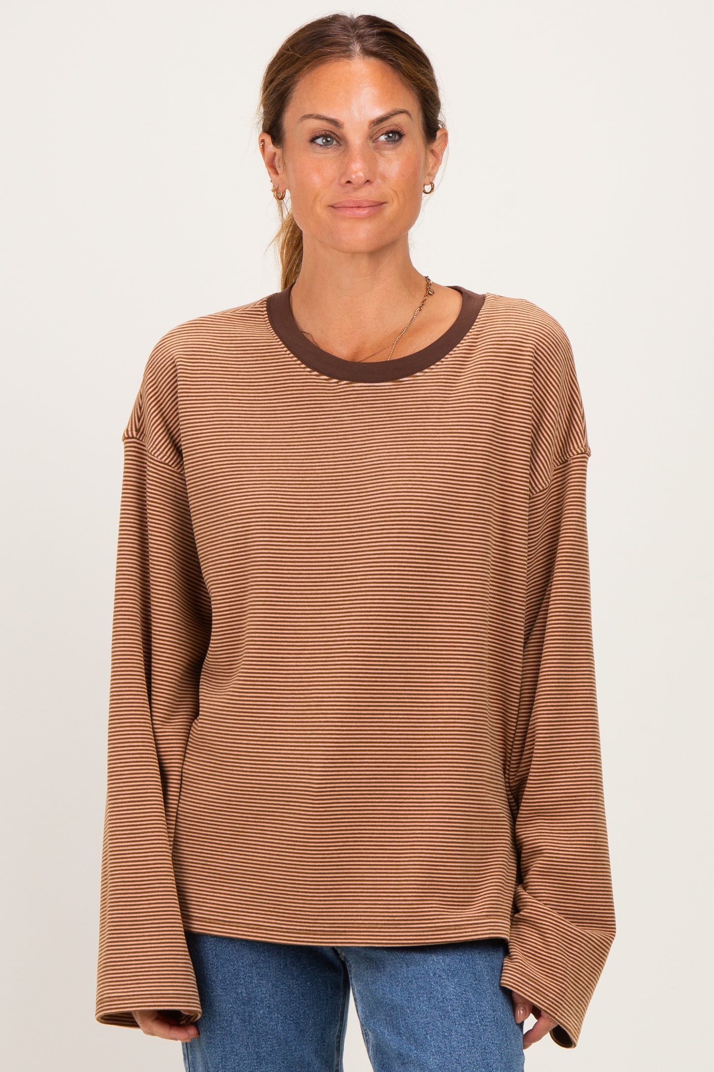 woman wearing a brown striped long sleeve top with a contrasting dark brown neckline and relaxed fit