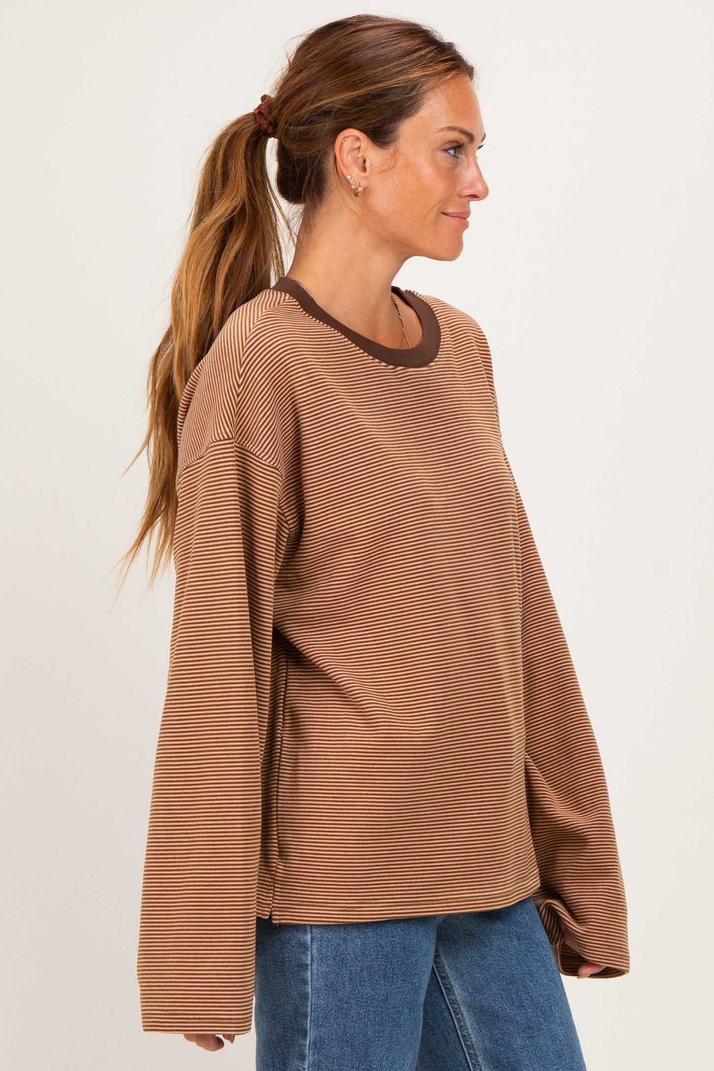woman wearing a brown striped long sleeve shirt with a ribbed neckline and relaxed fit