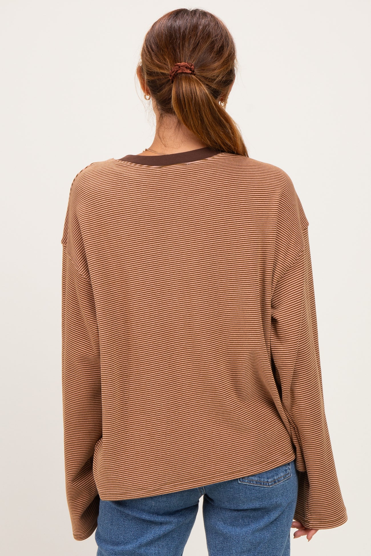 woman wearing a brown striped long sleeve oversized top with dropped shoulders and back view displayed