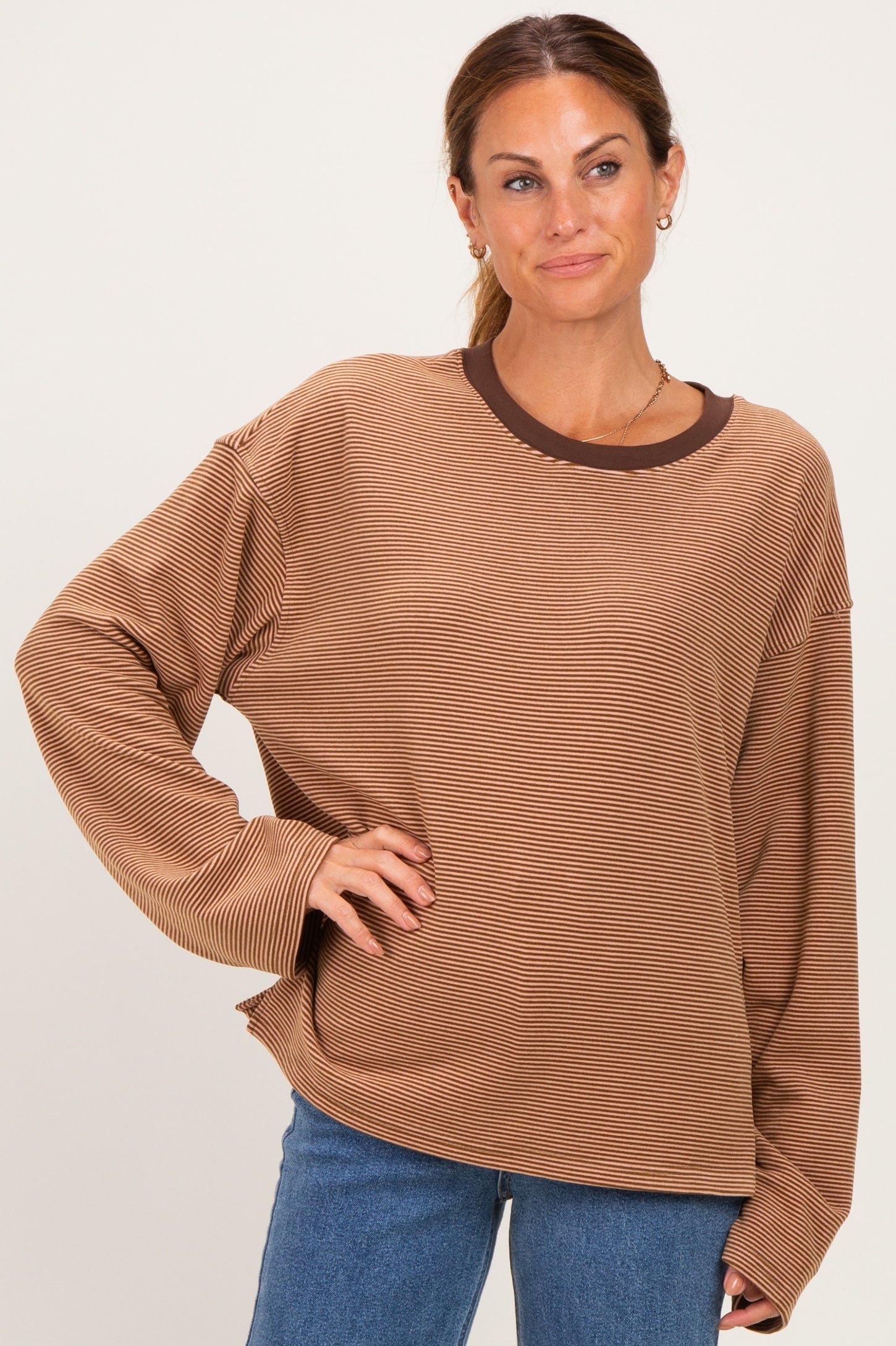 woman wearing a brown and tan striped long sleeve oversized top with a round neckline and relaxed fit