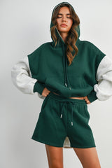 woman wearing a green and gray color block oversized hoodie with matching green shorts