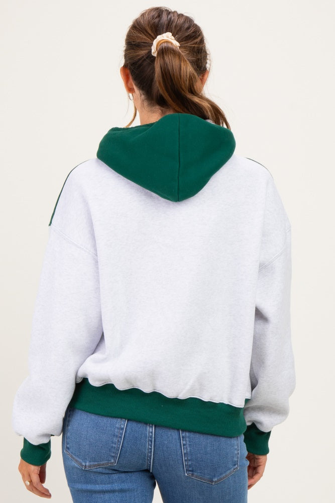 woman wearing a grey and green maternity hoodie, showing her back, styled with jeans