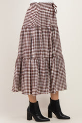 woman wearing a brown and white gingham tiered maxi skirt with a drawstring waist and black ankle boots