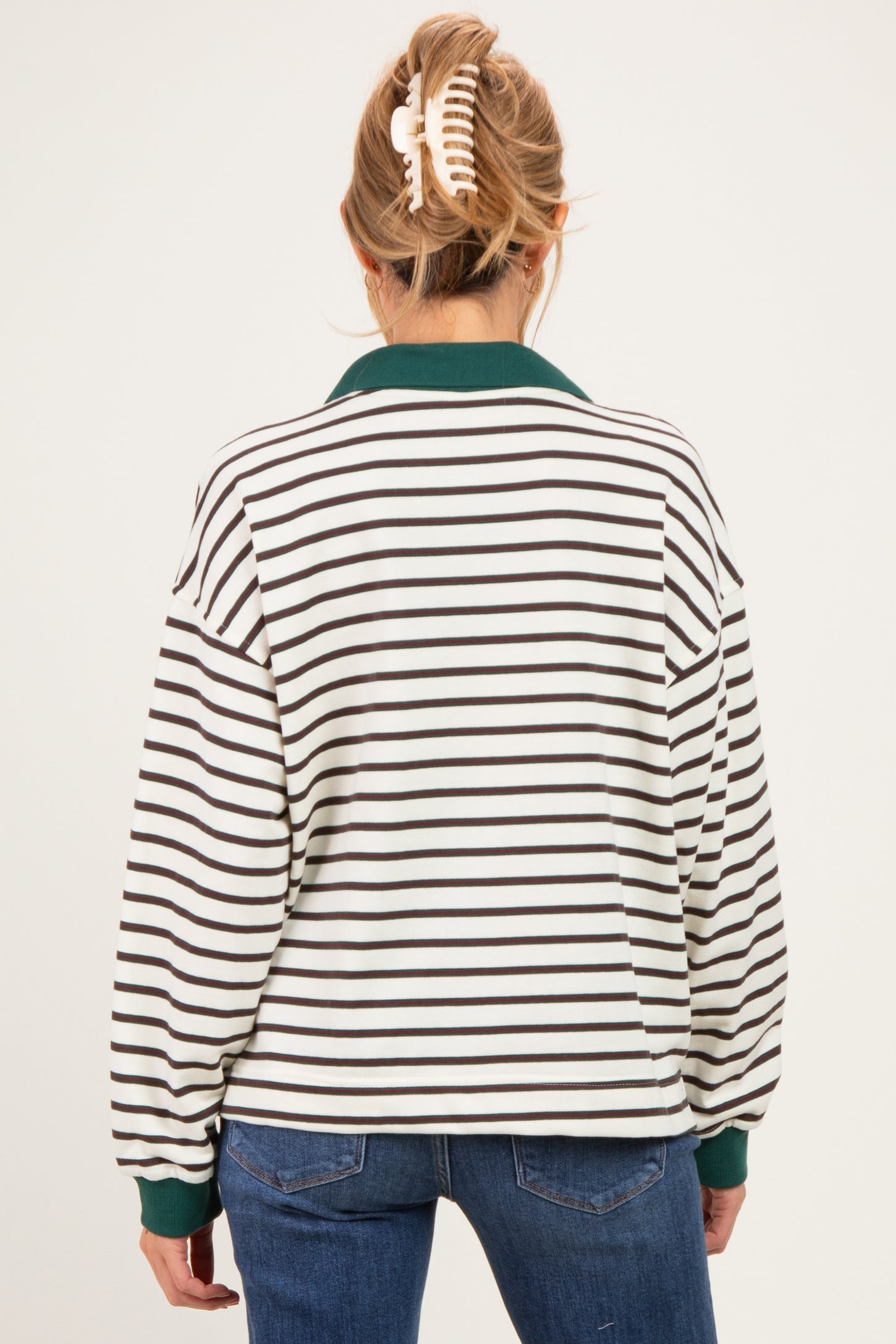 woman wearing a white and brown striped maternity pullover with a green collar, viewed from the back