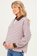 woman wearing a pink striped maternity sweatshirt with a brown collar and holding her baby bump