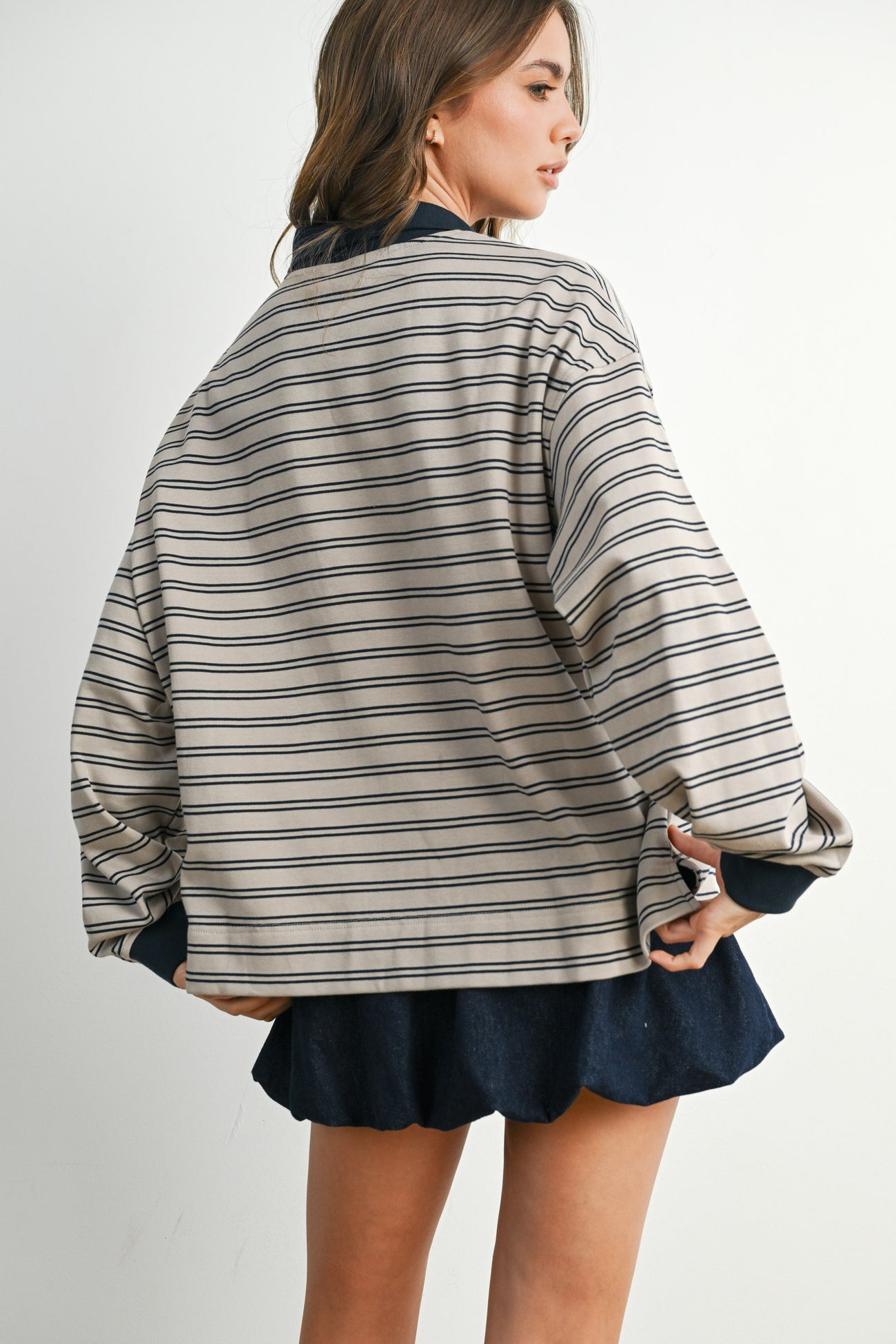 woman wearing a beige and navy striped oversized jacket with a relaxed fit and paired with a dark skirt