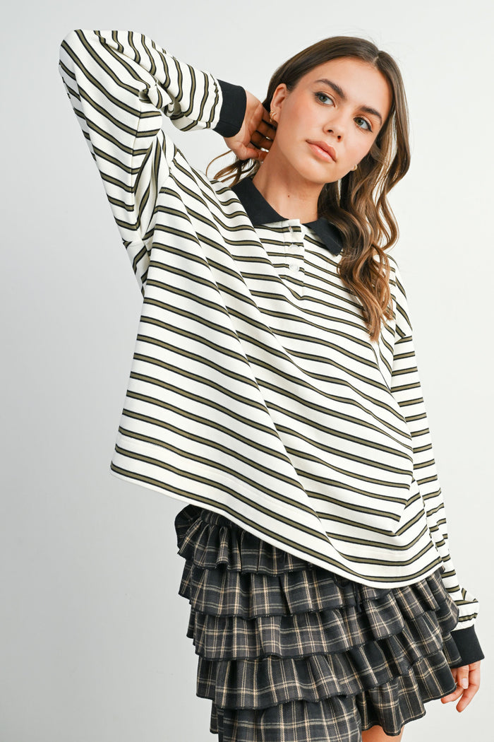woman wearing a white and black striped long sleeve polo top with a black collar and a tiered plaid skirt