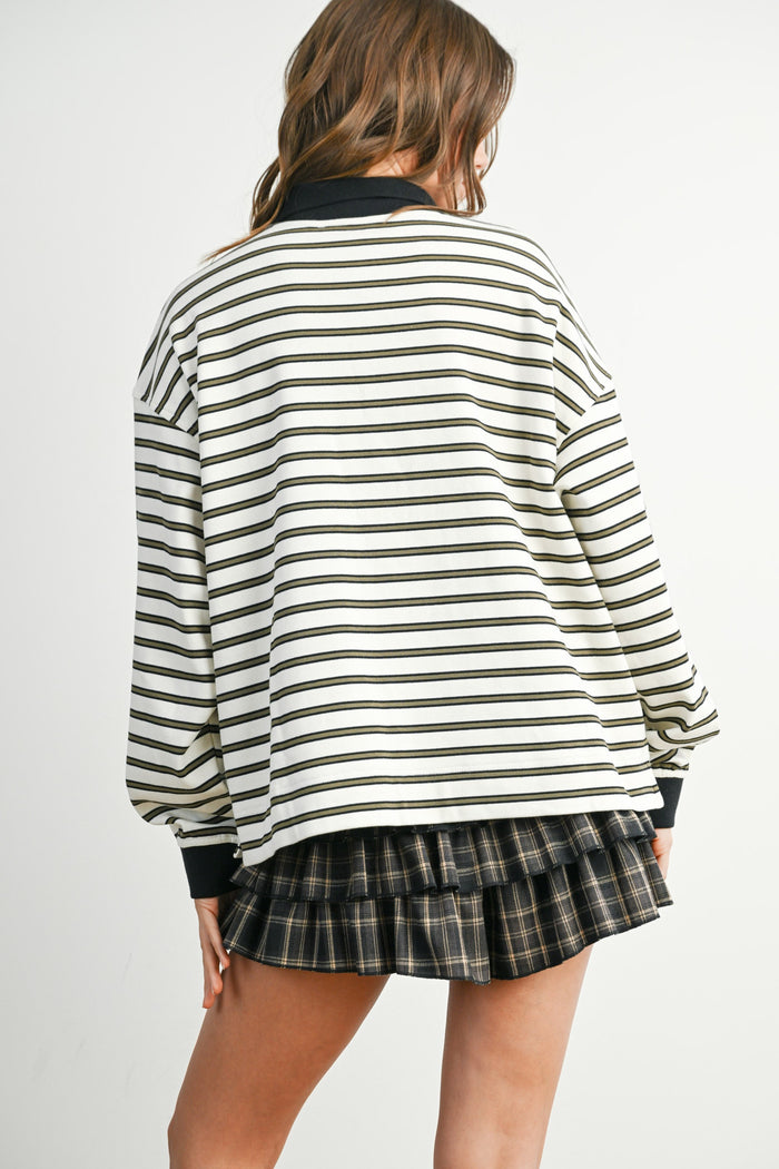 woman wearing a striped oversized sweater with black and white stripes and a black collar, paired with a plaid mini skirt