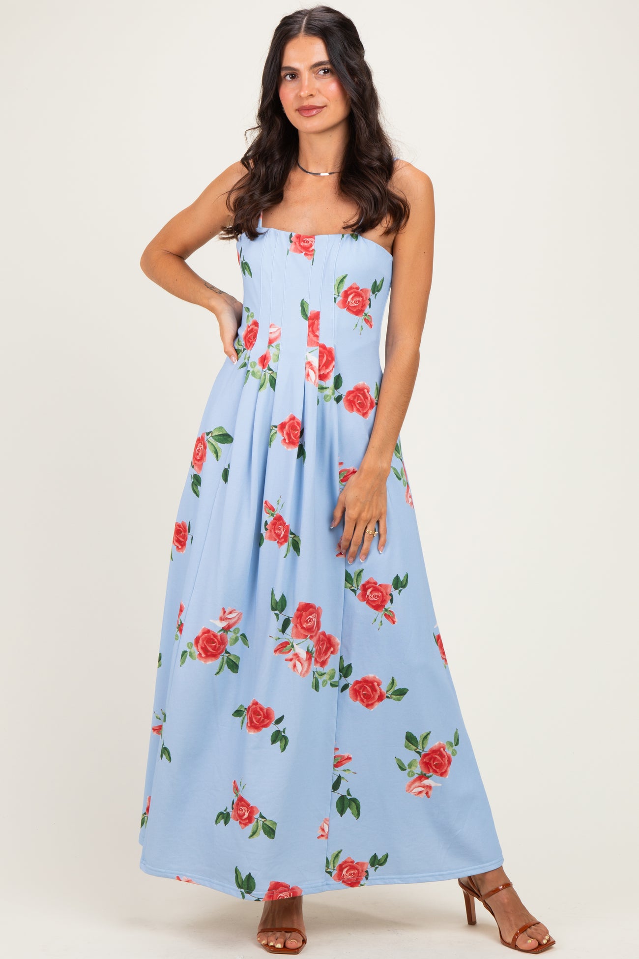 woman wearing a light blue floral maxi dress with red roses, styled with strappy heels