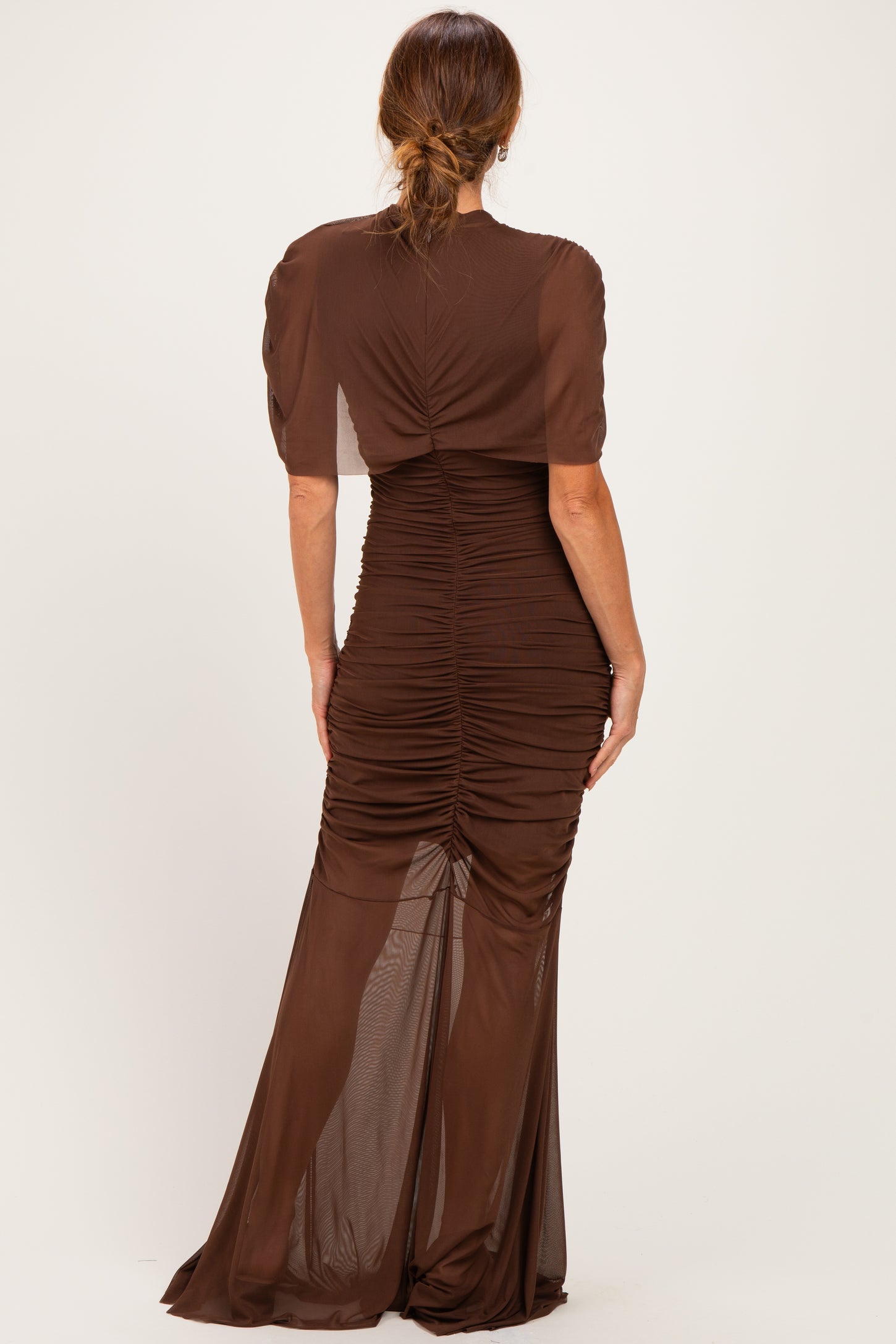 woman wearing a brown ruched maxi dress with sheer sleeves, viewed from the back