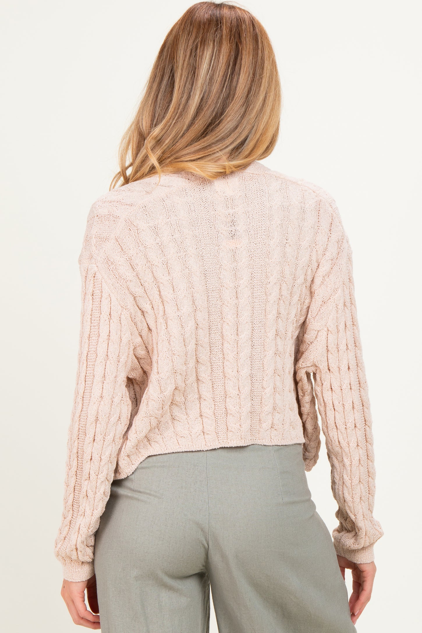 woman wearing a soft pink cropped cable knit maternity sweater, with back view displayed