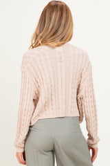woman wearing a soft pink cropped cable knit maternity sweater, with back view displayed