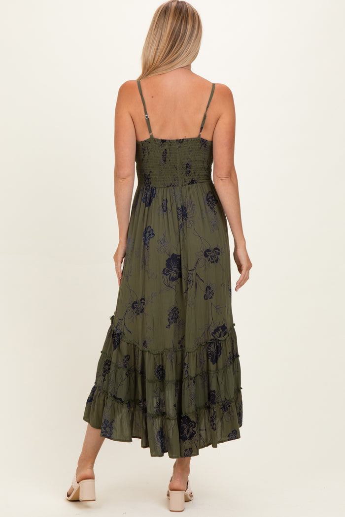 woman wearing an olive green floral maxi dress with ruffled layers and adjustable spaghetti straps, seen from the back