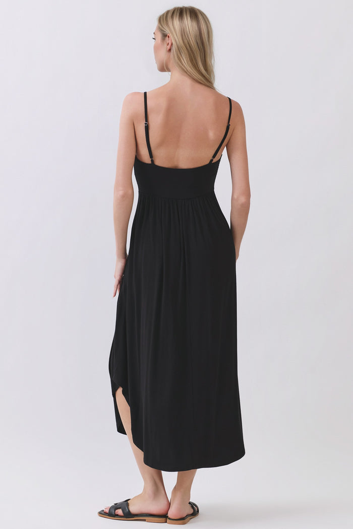 woman wearing a black maxi dress with adjustable straps and a side slit, shown from the back
