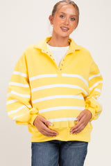 woman wearing a yellow striped maternity sweatshirt with a collared neck and holding her baby bump