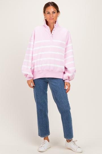woman wearing a pink striped oversized pullover sweatshirt with a quarter zip and relaxed fit jeans
