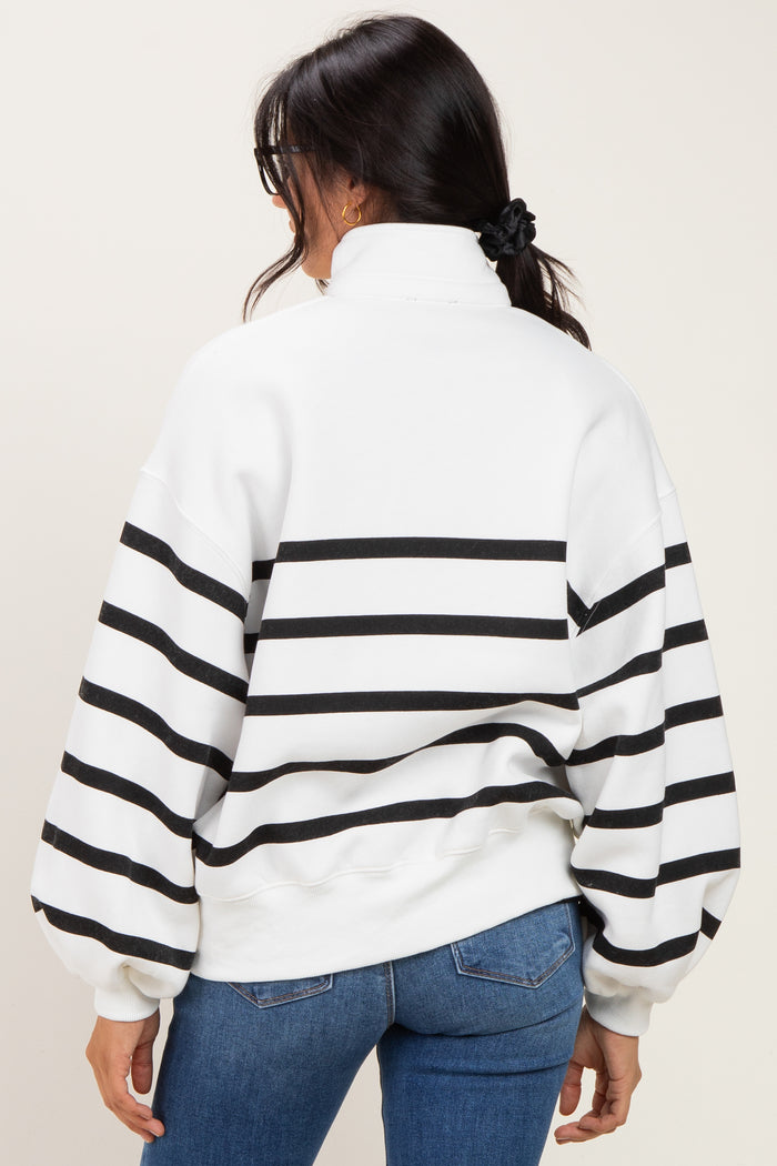 woman wearing a white and black striped oversized sweatshirt with a high collar and balloon sleeves