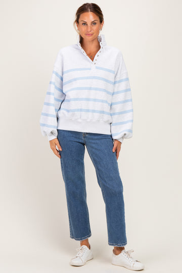woman wearing a light gray striped sweatshirt with a collar and button placket paired with blue high-waisted jeans