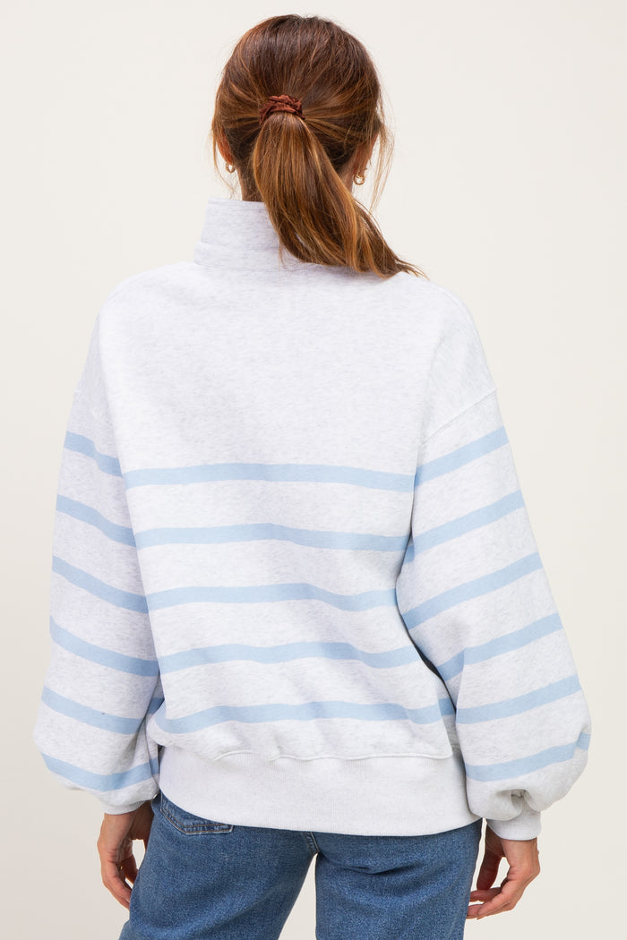 woman wearing a gray and light blue striped oversized sweatshirt with a high neck and balloon sleeves