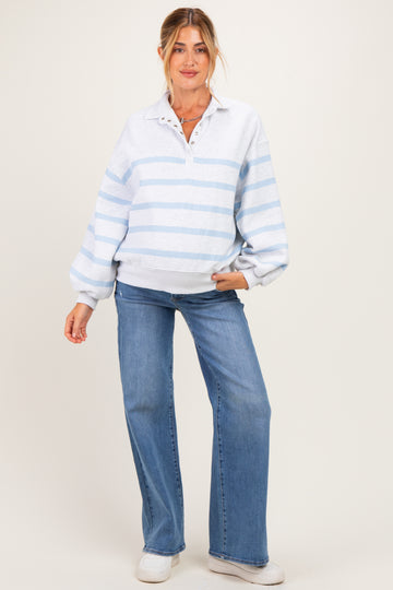 woman wearing a light gray and blue striped maternity pullover with a collar and relaxed fit, paired with flared jeans