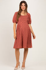 woman wearing a rust-colored maternity dress with black polka dots and puff sleeves