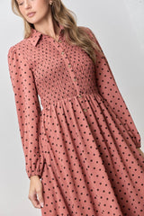 woman wearing a pink long sleeve shirt dress with polka dots and a smocked bodice