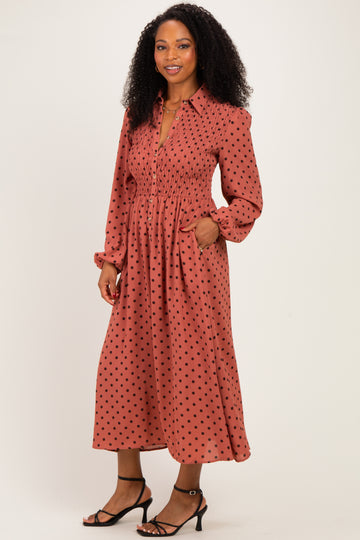 woman wearing a rust polka dot long sleeve dress with a smocked waist and pockets, styled with strappy heels