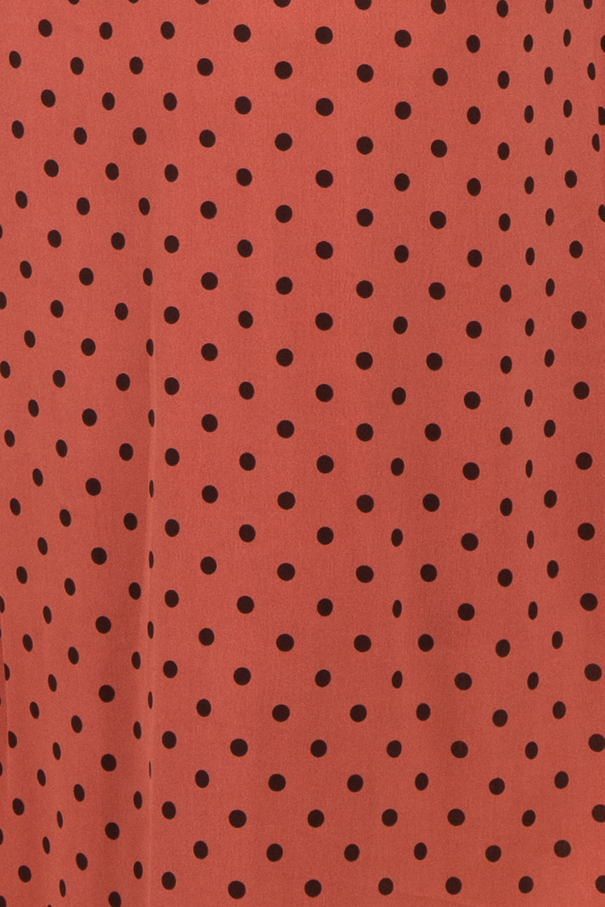 rust polka dot fabric with black spots, suitable for various clothing styles