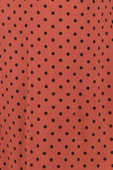 rust polka dot fabric with black spots, suitable for various clothing styles