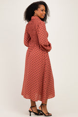 woman wearing a rust colored midi dress with black polka dots and smocked detailing, styled with strappy black heels