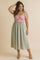 woman wearing a floral print midi dress with a pink bodice and green skirt, styled with a shoulder tie and wedge sandals