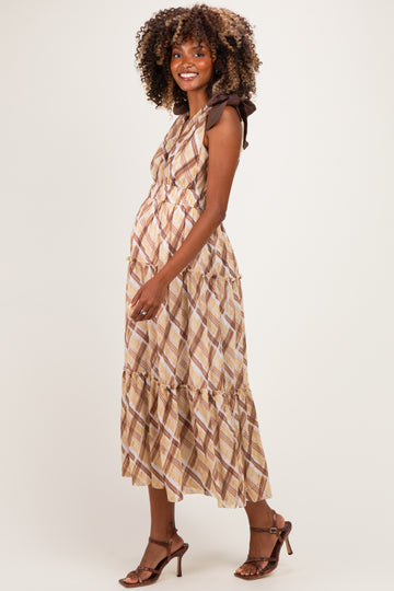 woman wearing a brown and cream patterned maternity maxi dress with tie straps and a visible baby bump