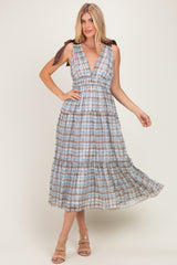 woman wearing a blue and brown plaid maxi dress with a deep v-neck and tie shoulder straps