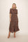 woman wearing a brown floral midi dress with short sleeves and a tie neck detail