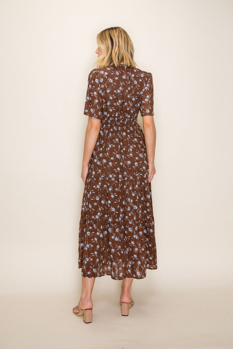woman wearing a brown floral midi dress with short sleeves and a tiered skirt, shown from the back