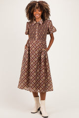 woman wearing a brown plaid maternity dress with short puff sleeves and pockets