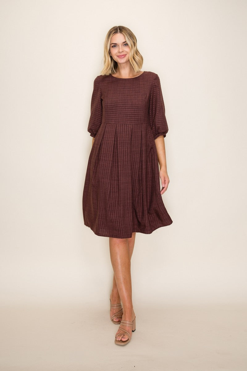 woman wearing a burgundy textured dress with three-quarter sleeves and a flared skirt