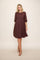 woman wearing a burgundy textured dress with three-quarter sleeves and a flared skirt