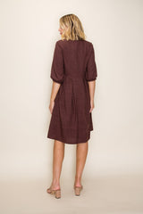 woman wearing a brown textured dress with puff sleeves and a flared skirt, shown from the back