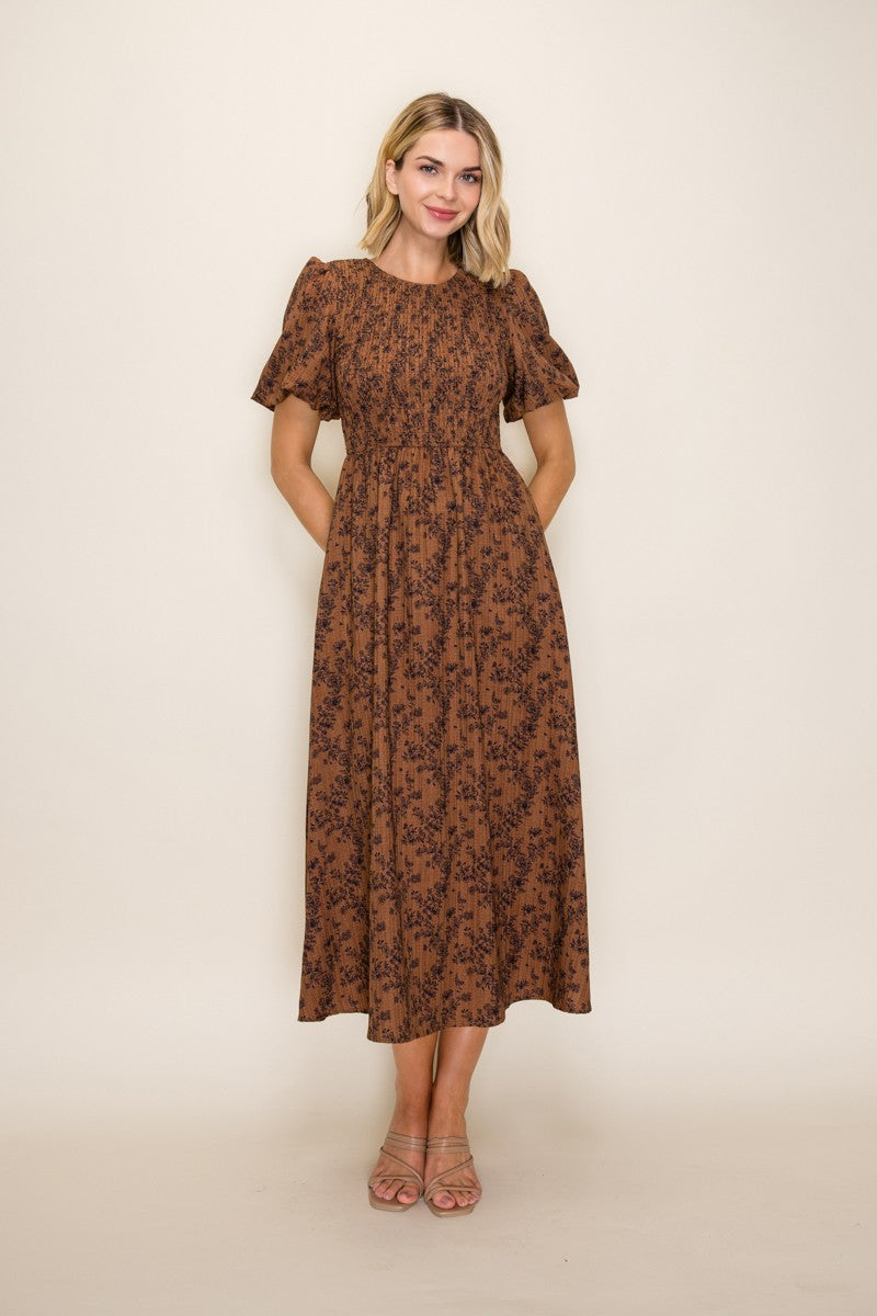 woman wearing a brown floral midi dress with puff sleeves and pockets
