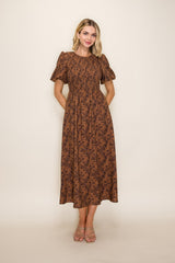 woman wearing a brown floral midi dress with puff sleeves and pockets