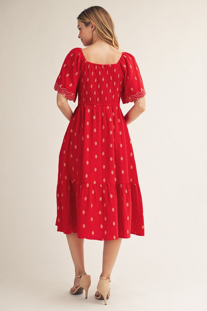 woman wearing a red midi dress with puff sleeves and golden embroidery, showing a back view