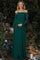 woman wearing a green lace off-shoulder maternity gown and cradling her baby bump in a garden setting