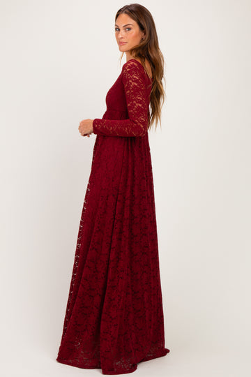 woman wearing a burgundy lace long sleeve maxi dress with a flowy silhouette and side slit