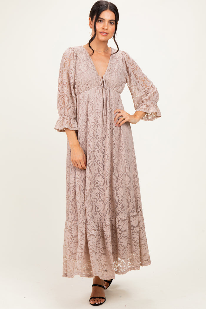 woman wearing a blush lace maxi dress with bell sleeves and a cinched empire waist