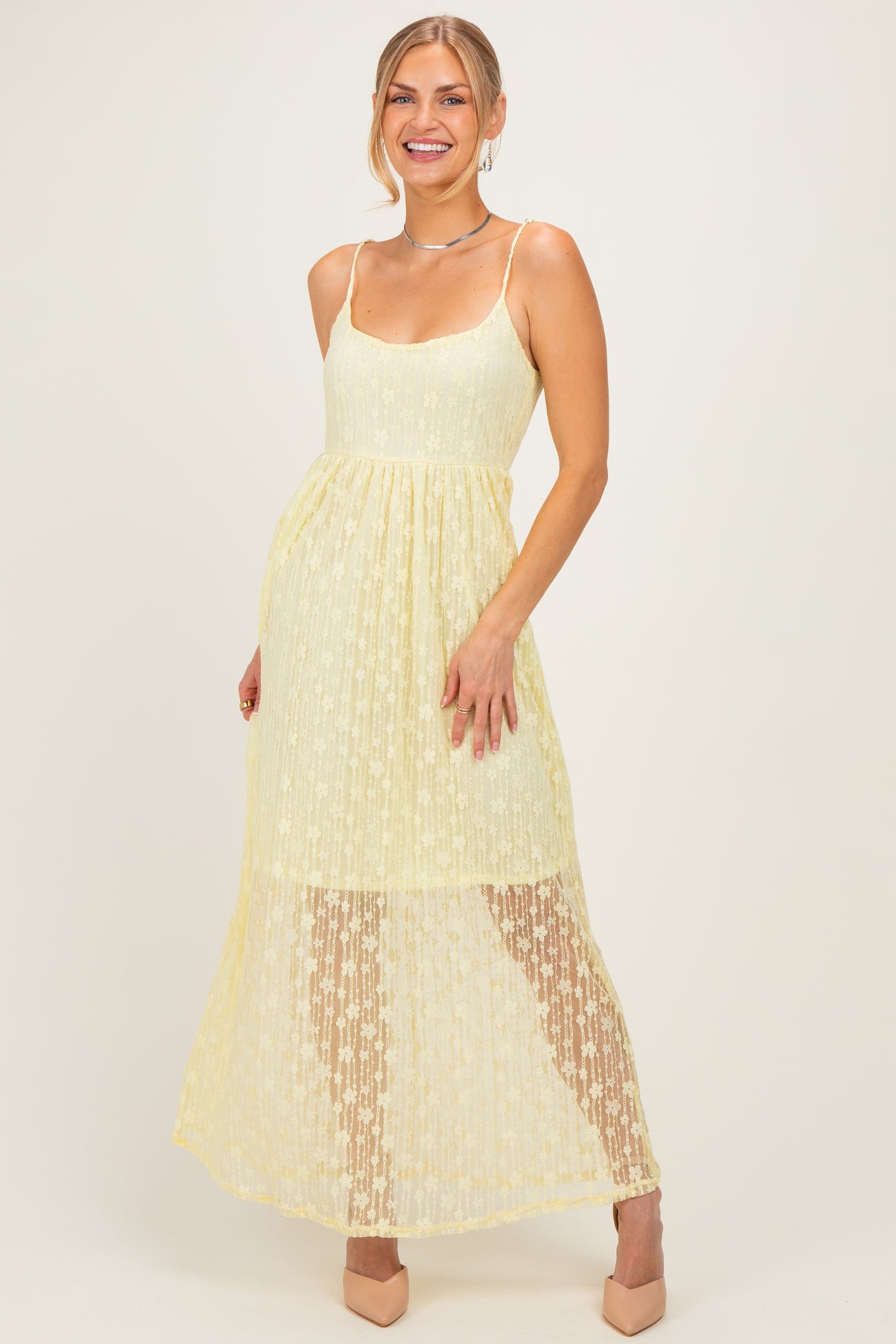 woman wearing a yellow lace maxi dress with a fitted bodice and flowy skirt, posing and smiling