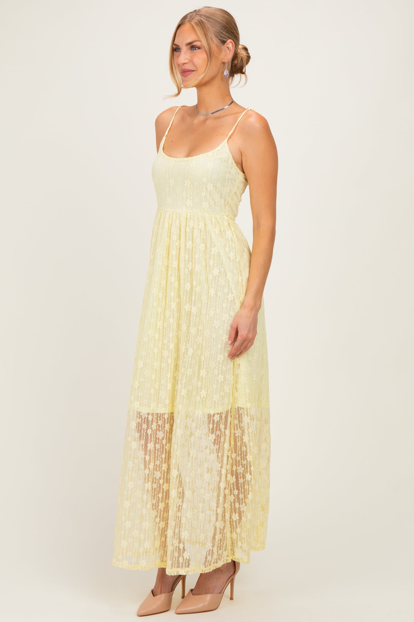woman wearing a light yellow maxi dress with a sheer lace overlay and spaghetti straps